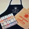 Black apron with curry on cooking logo with wording Keep Korma and Curry On with a cream shopper and 8 Curry On Cooking curry kits